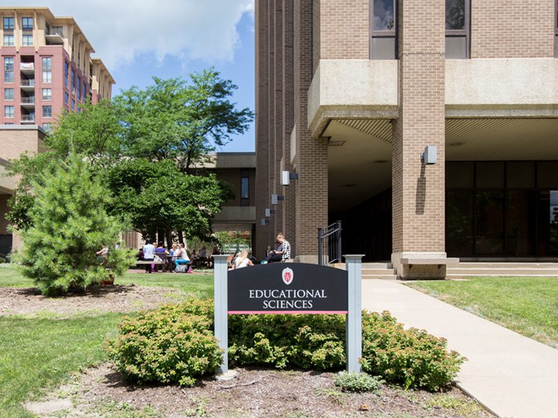 A sign in front of some greenery and a building stating, "Educational Sciences".