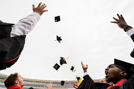 Graduating students tossing their hats up in cheer.