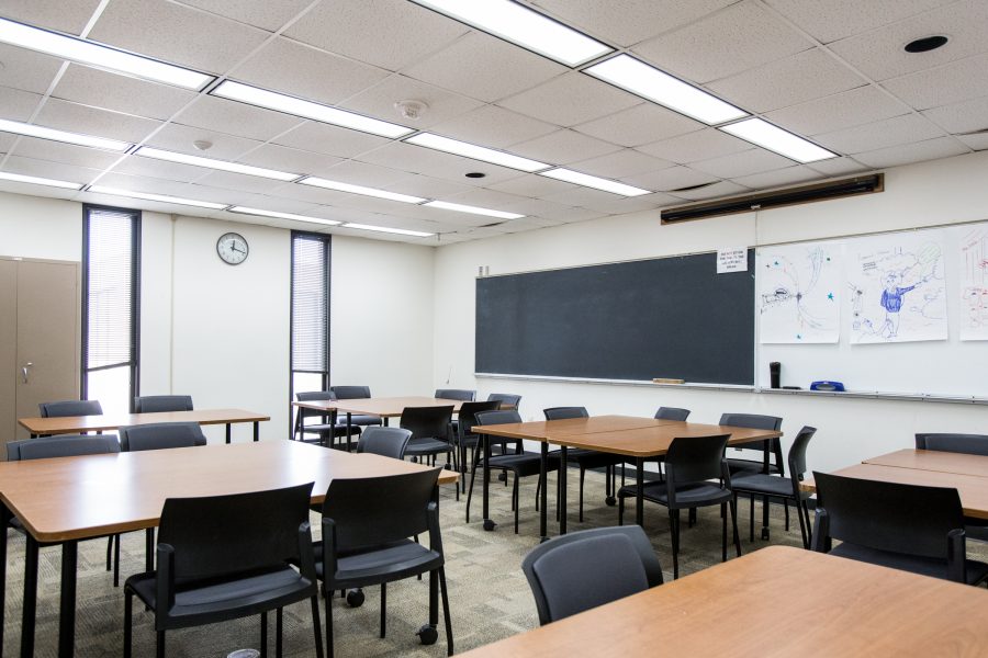 Empty classroom with tables, chair, and boards on the wall