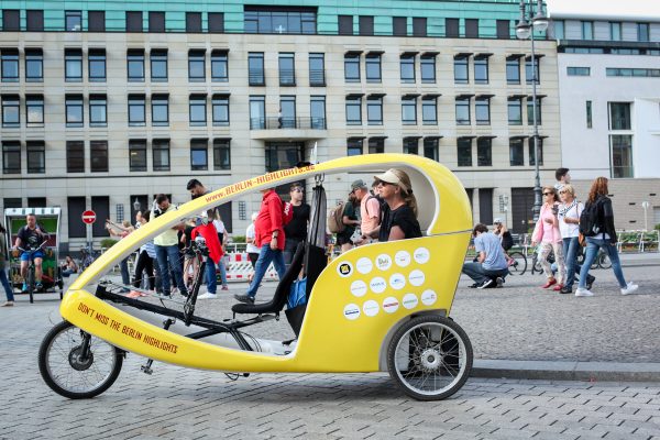 Yellow bike mobile with no doors with woman inside placed in city.