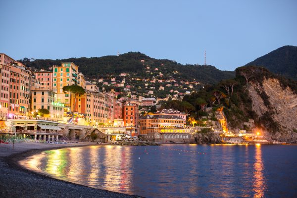 Beach view overlooking water with city and lights.