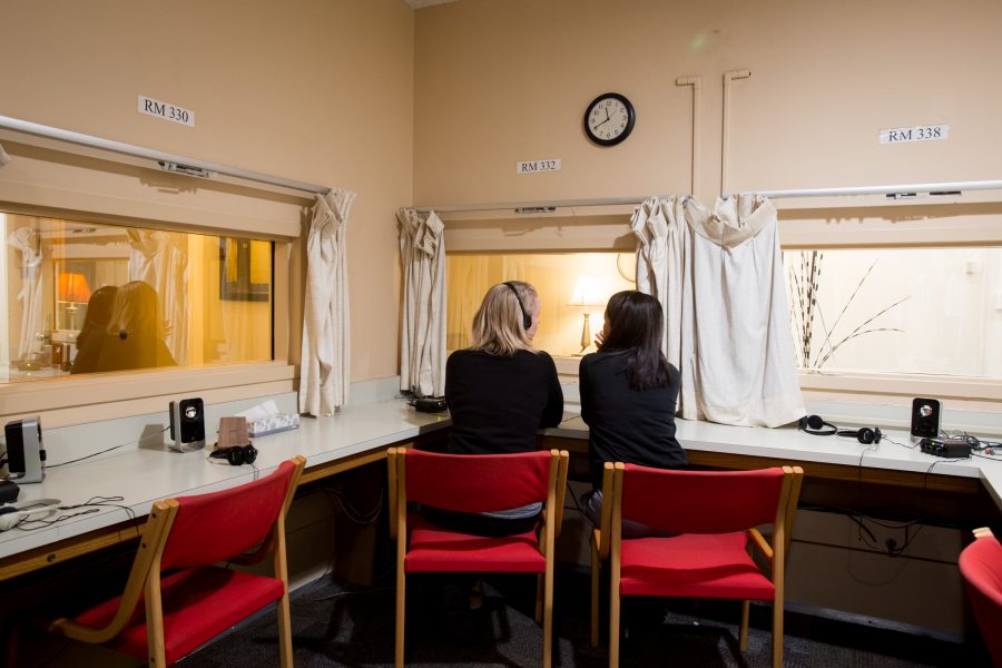 A blonde woman talking to a brunette woman as they both sit on red chairs.