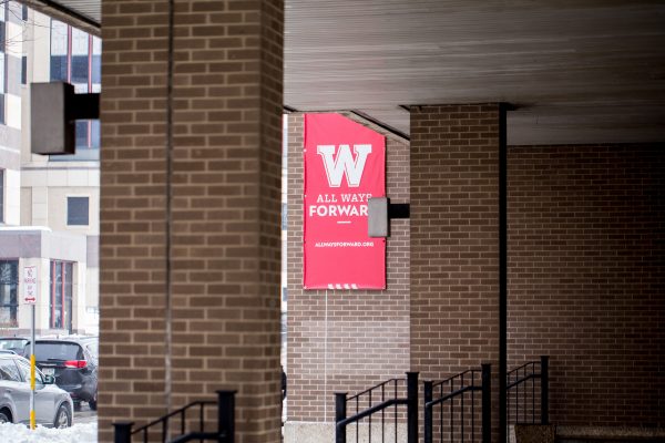 Brick columns in front of wall with red "W All Ways Forward" flag.