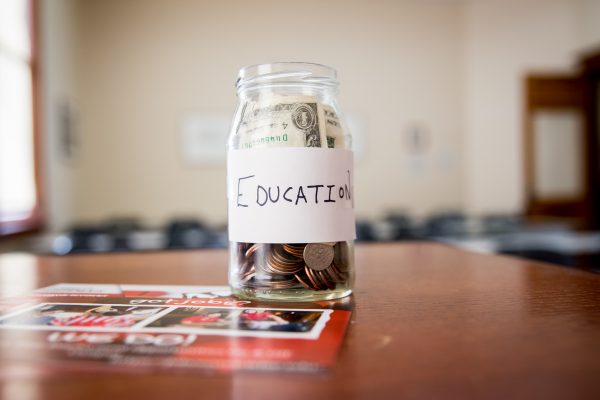 Coins and dollars inside jar labeled "Education" on table