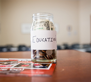 Coins and dollars inside jar labeled "Education" on table