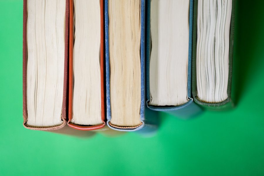 3 books leveled evenly with spine facing up, 2 leveled higher against a green background.