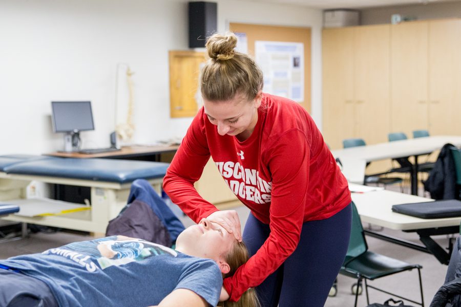 Student checking other student laying down temperature.