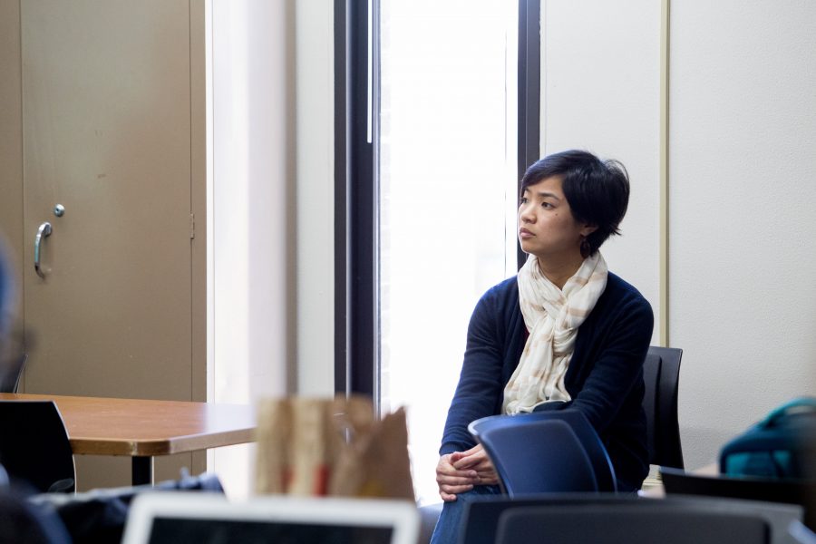 Woman sitting down in chair watching someone speak.