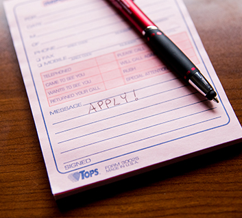 A pad of forms with a pen and the text "apply!" written on it.