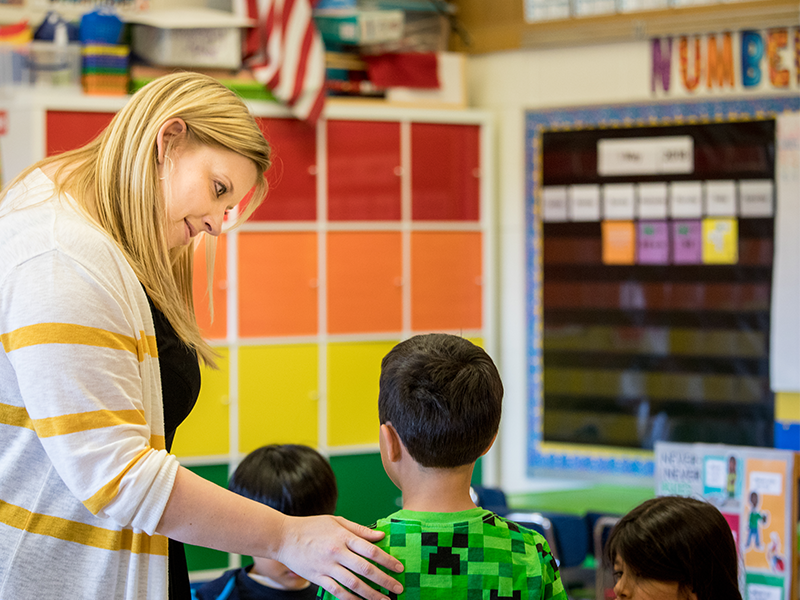 Teacher speaking with student in a classroom