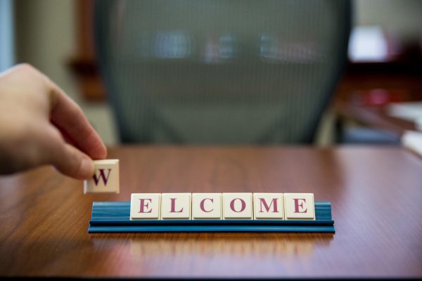 Hand placing down W tile spelling "welcome" on desk.