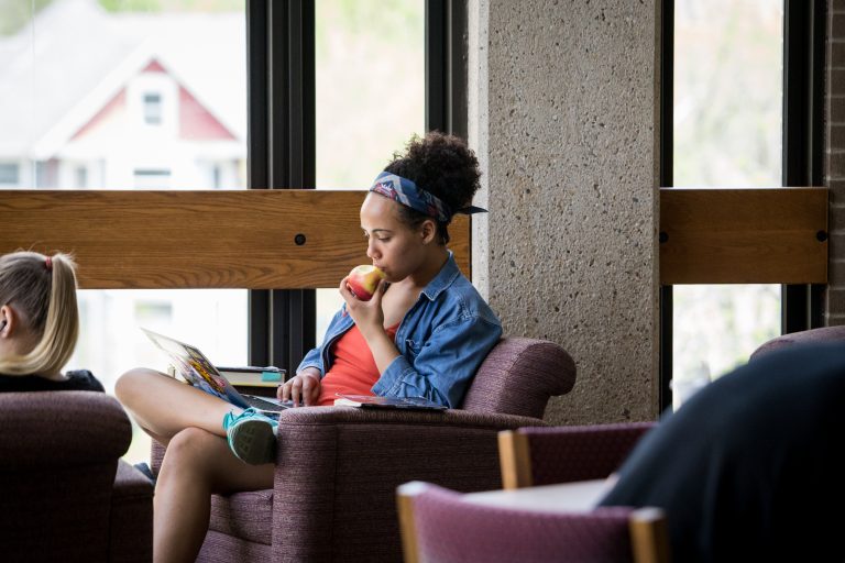 Student studying in the Merit Library eating an apple.